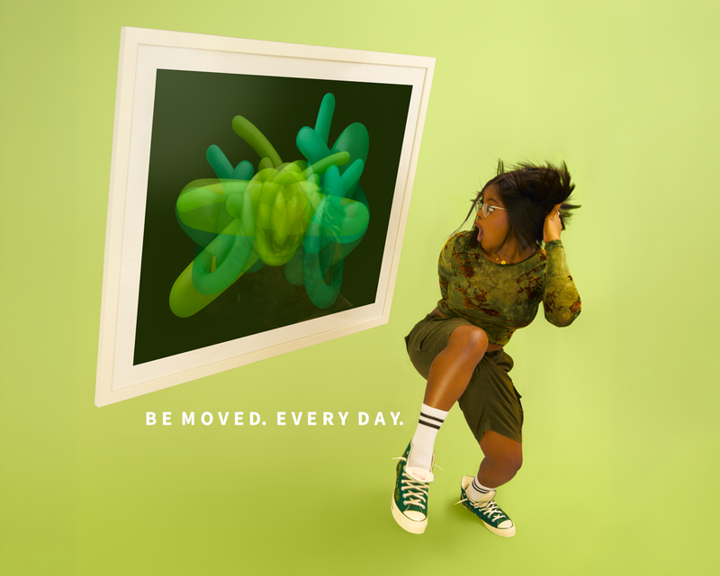A beautiful woman  in a camouflage long-sleeve top, olive shorts, white socks, and green sneakers poses next to a large framed abstract art print featuring green and teal shapes on a dark background. The scene is set against a solid light green wall with the text 'BE MOVED. EVERY DAY.
