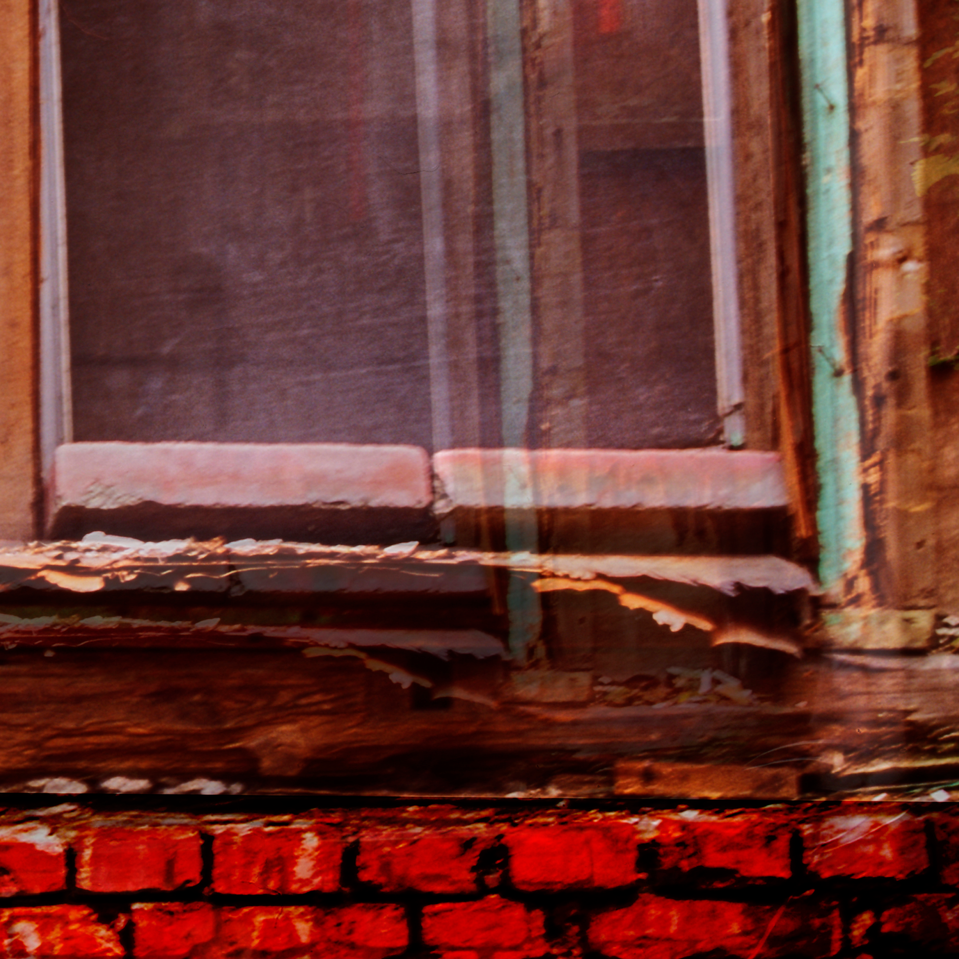 Rustic wooden window frame with peeling paint against a brick wall.
