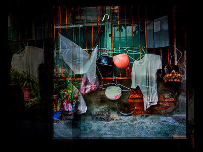 Multiple exposure of Hanging clothes in front of a metal gate with a pink object on a string in Taiwan