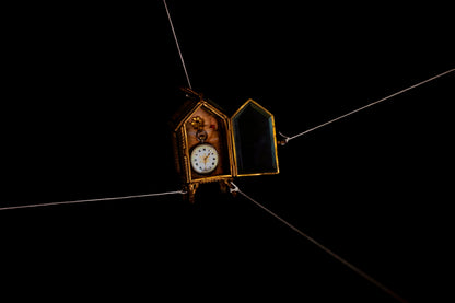 Decorative clock hanging from a string against a dark background