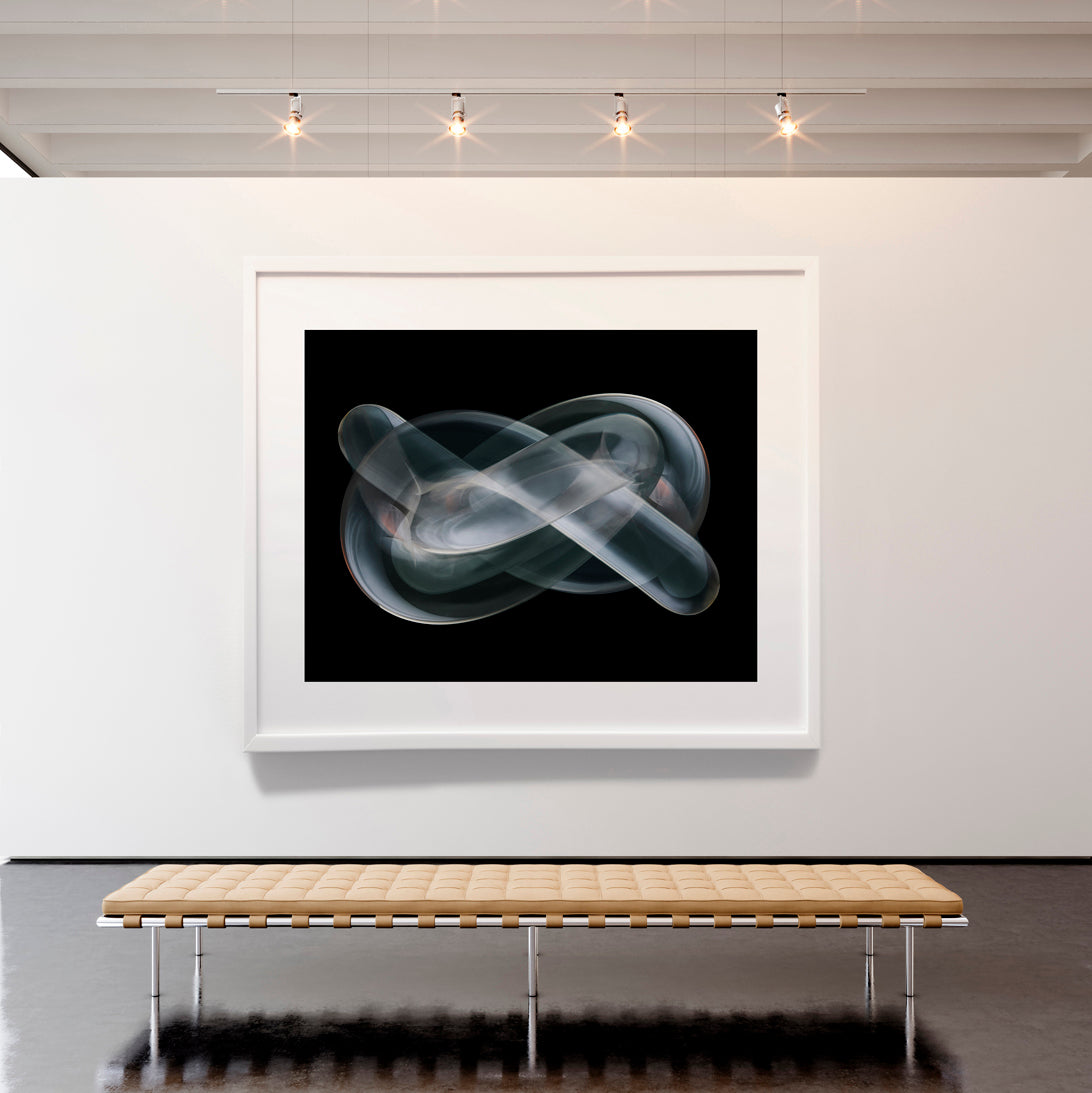 Framed abstract art piece on a white wall above a wooden bench.