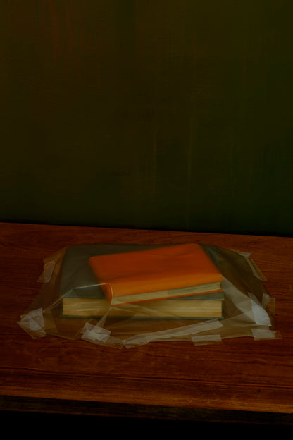 Stack of books on a wooden surface wrapped in plastic like a memory with a dark background